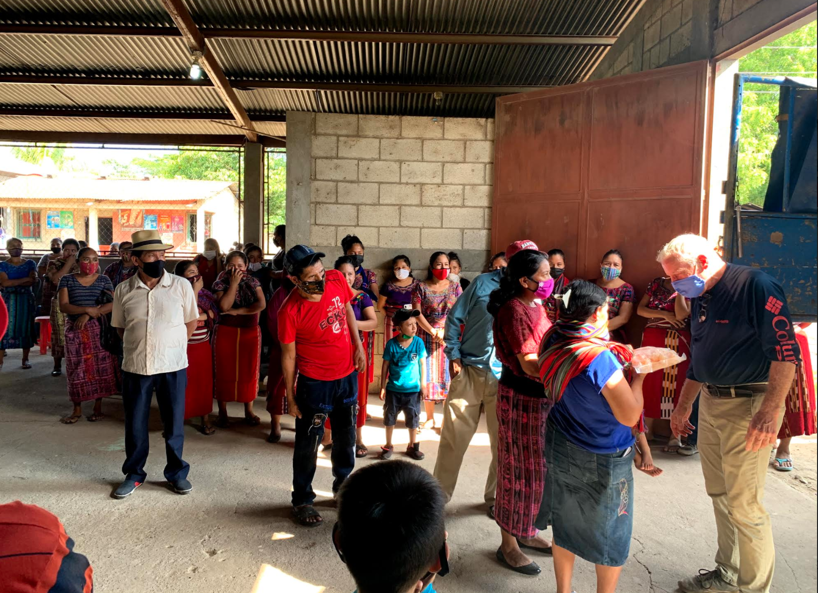men and women of El Triungo in traditional dress greet Mike Corser to unload truckload of frozen seafood